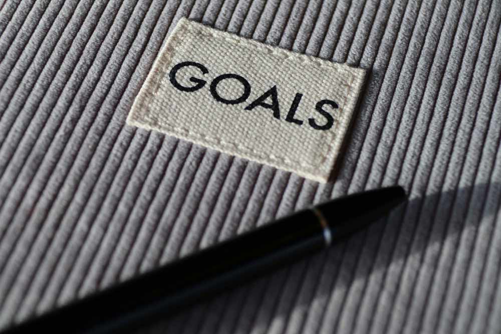 Overcoming limiting beliefs for career growth—“Goals” label with pen on textured surface, representing mindset coaching, self-awareness, and breaking mental barriers that hold professionals back from advancement and new opportunities.