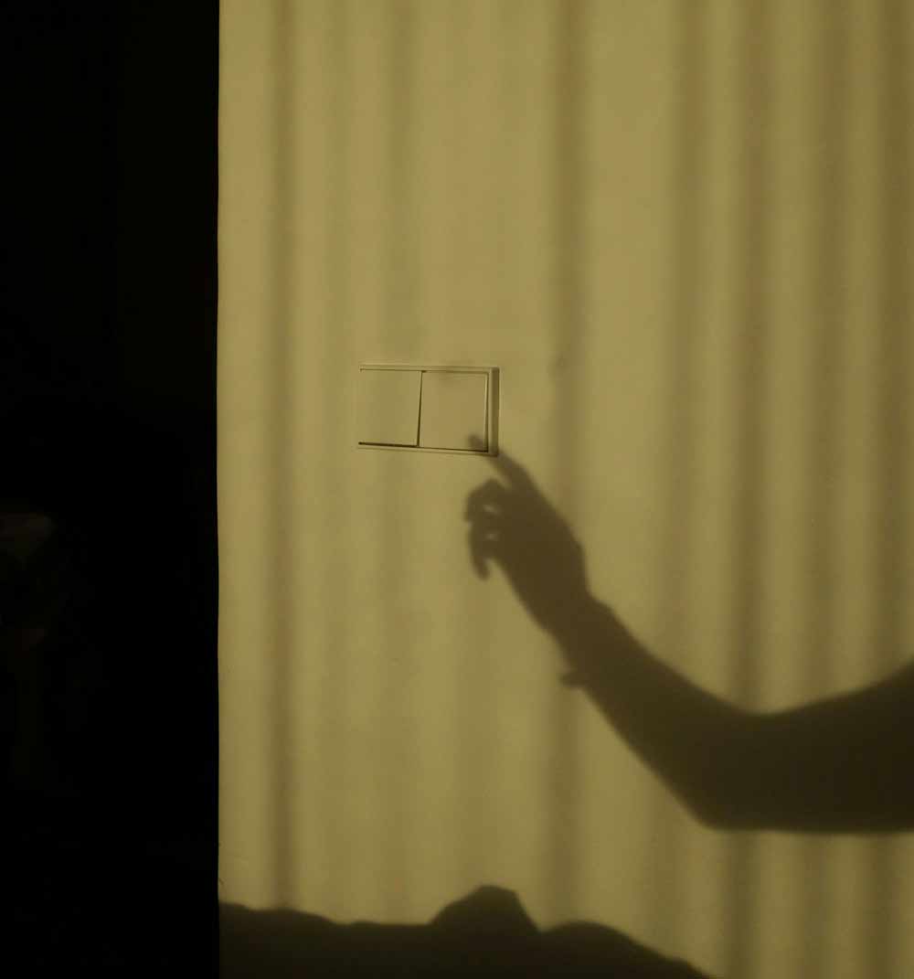 Energy-efficient HVAC systems in Jacksonville, Jacksonville Beach, and Neptune Beach—hand reaching toward a light switch in a dim room, symbolizing energy savings, reduced utility bills, and smarter home efficiency through upgraded heating and cooling systems.