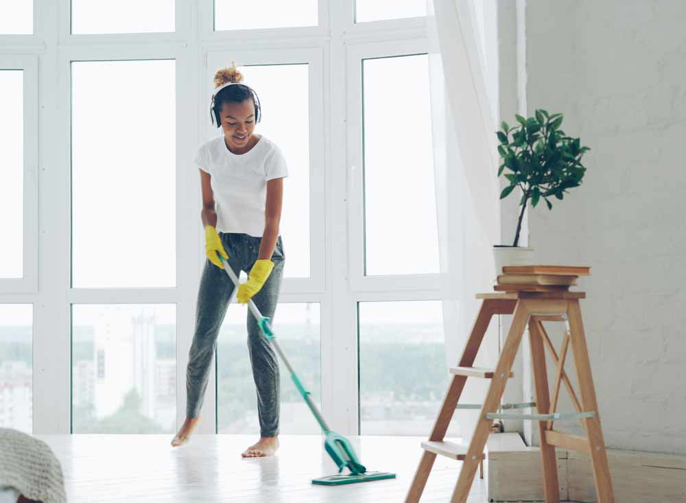 Move-in cleaning in Jacksonville Beach—woman mopping bright, modern home interior with large windows, illustrating professional deep cleaning services typically costing $150–$400 depending on home size, condition, and add-ons like oven, refrigerator, and window cleaning.