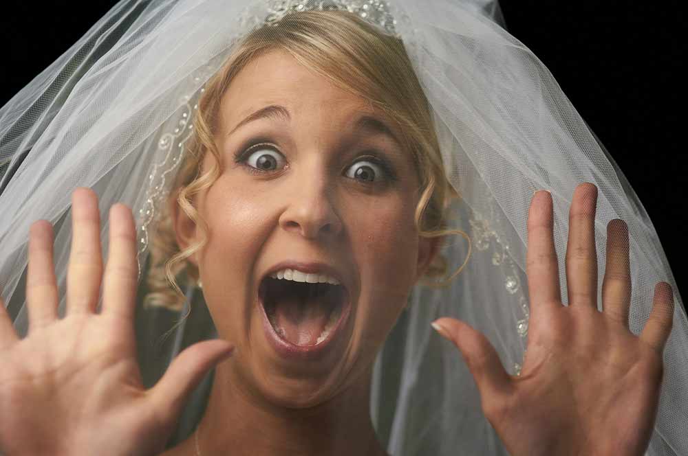 DIY wedding videography challenges—bride with an expressive, surprised reaction, symbolizing the unexpected stress, technical difficulties, and hidden costs couples may face when attempting to capture their own wedding moments without professional support.